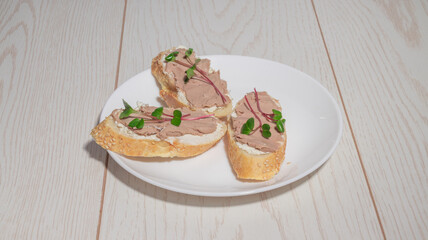 A close-up of a p�-covered baguette slice, highlighting the creamy texture and fresh microgreens on top.
