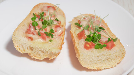 A plate with different variations of open-faced sandwiches, including cream cheese with walnuts and melted cheese with tomatoes and microgreens.