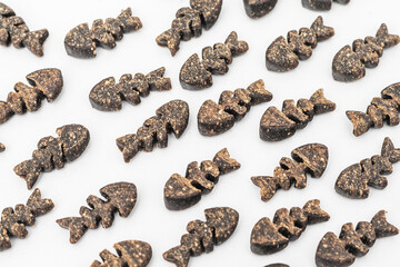 Close-up of fish-shaped pet treats made from natural ingredients, scattered on a white background.