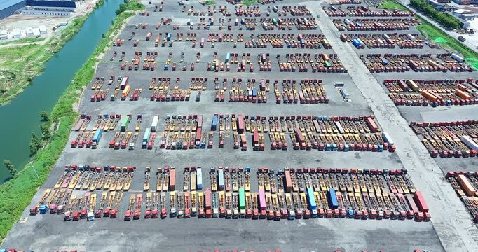 Aerial view of a massive truck trailer parking lot and container yard near a waterway, logistics hub