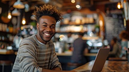 Obraz premium Man smiling while working on a laptop in cozy cafe. Warm lighting and modern ambiance provide perfect setting for remote work or relaxation.
