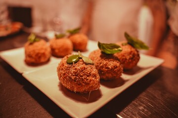 Series of dishes coming out of the kitchen with mozzarella-filled supplì during an evening event in an Italian pizzeria