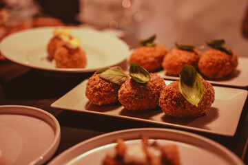 Series of dishes coming out of the kitchen with mozzarella-filled supplì during an evening event in an Italian pizzeria