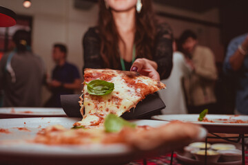 detail of a girl taking a slice of margherita pizza from the tray placed on a table set aside for food at an evening event at the restaurant