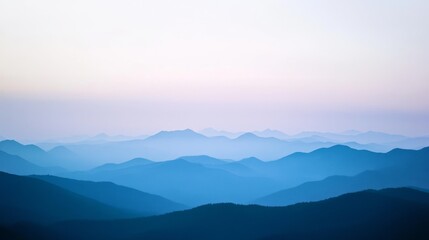 Fototapeta premium Misty blue hills stretch across the horizon, enveloped in a tranquil twilight glow under a pastel sky.