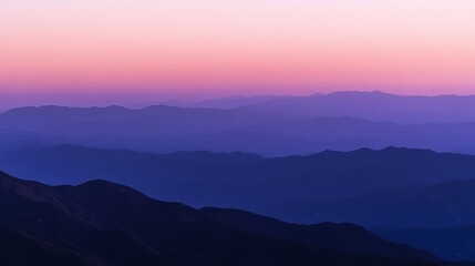 Fototapeta premium Layers of distant mountains fade into the horizon under a serene, gradient dusk sky, embodying tranquility and vastness.