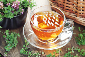 Thyme herbal tea in a glass cup with flowers on wooden rustic background, closeup, natural medicine and naturopathy concept