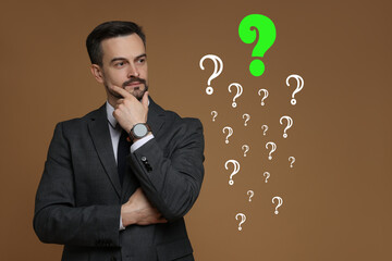 Thoughtful businessman looking at question marks on brown background