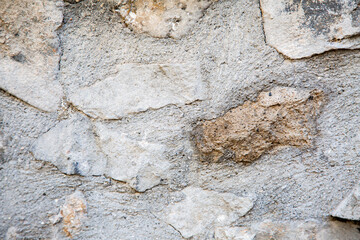 A detailed closeup view of a textured stone wall featuring numerous rocks