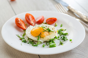 Fried eggs with cherry tomatoes and greens for breakfast