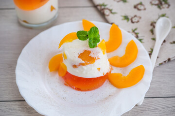 Pieces of canned peaches inside multilayer jelly on wooden table