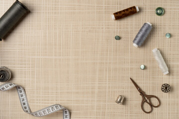 Sewing accessories frame on the table. Measuring tape, thread, buttons, scissors, thimble, bobbin. Flat lay, top view. Copy space