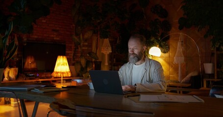 Night work from home. A man uses a laptop sitting at a desk
