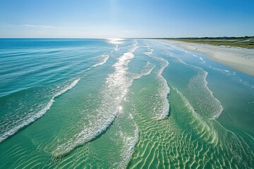Crystal-clear turquoise water gently rolls ashore on a pristine sandy beach under a vibrant blue sky.