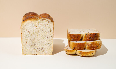 Freshly baked whole grain bread with slices on beige and white background close up.