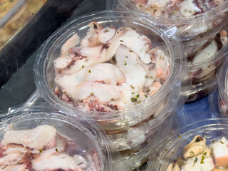 Freshly sliced squid in marinade in clear plastic containers