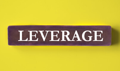 LEVERAGE - word on a wooden block close-up on a yellow background
