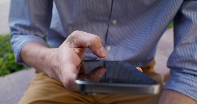 The businessman uses a mobile phone. Close-up from his hands to his face