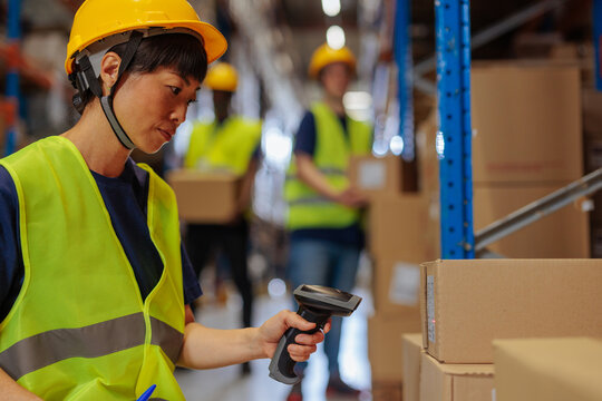 Female Asian warehouse worker scanning the packages