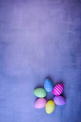 Easter composition with multi-colored decorative eggs, decorated with patterns, on a background with a purple texture.