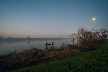 winter sunset over the Scardovari lagoon with fishing boats and cabins inside the delta of the...