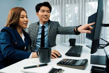 Asian business partners pointing to profit highest dynamic stock exchange data on computer screen value rate online website program. Investor showing financial on real time at modern office. Infobahn.