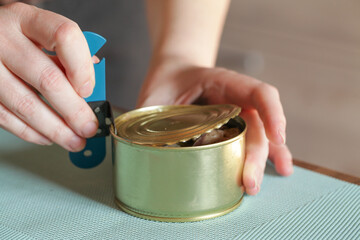 Womans hands open tin can with an can opener. Canned food and special knife