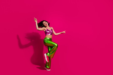 Vibrant young woman dancing in metallic outfit with magenta background