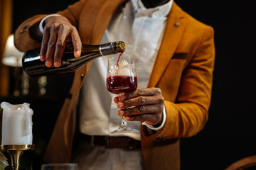 Waiter pouring red wine into crystal glass in restaurant