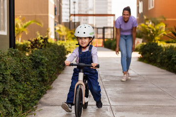 Madre enseñando a su hija a montar bicicleta de equilibrio dentro del condominio