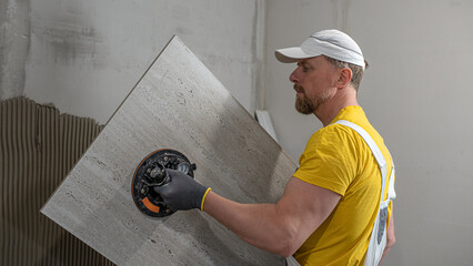 Tiling with large format tiles. A tiler placing a tile held by a tile suction cup.