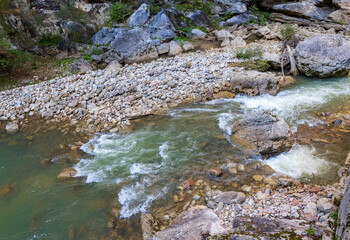 a stream of water in a stone riverbed, spewing noise and rumbling, making its way to free water