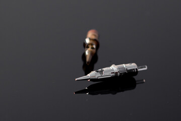 Permanent makeup. Needles for permanent makeup lie on a glass black background. Close-up.