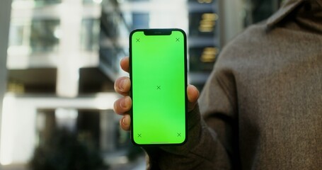 Close-up of a mobile phone with a screen forward in the hands of a young man, no face. Copy space, green screen, chroma key, mockup. Video in 4k, red komodo
