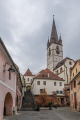 29 october 2024, sibiu, Romania. View from Strada Turnuliu street towards Sibiu Lutheran Cathedral, Catedrala Evanghelică Sfânta Maria. Brick wall in the foreground.