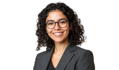 Confident Professional: A headshot portrait of a sophisticated woman with curly dark hair, eyeglasses, and a warm smile, wearing a smart suit, exuding professionalism and approachability.