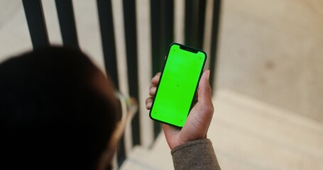 An African American man holds a mobile phone with a green screen in his hand. Video filming from...