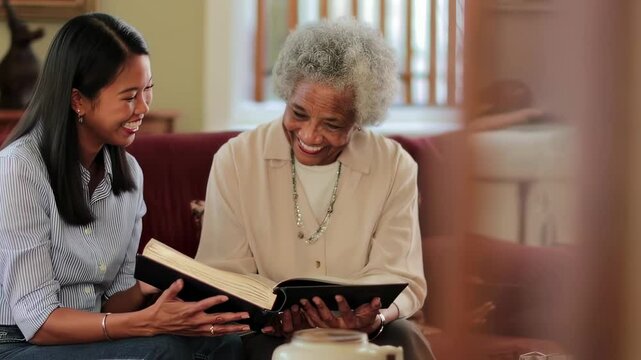 Daughter and senior mother sharing a laugh while reading a book