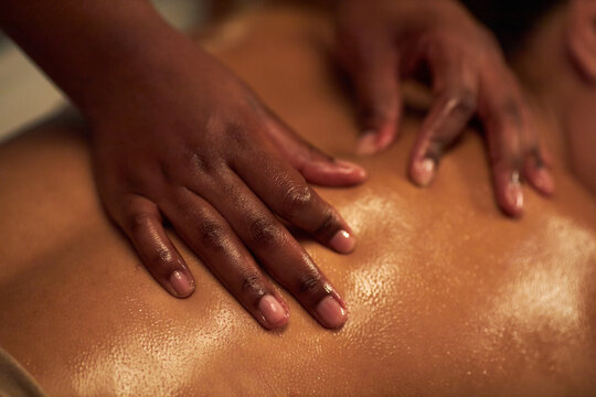 Close-up of hands providing relaxing therapeutic back massage in spa, shining skin signifying use of oils for enhancing massage experience