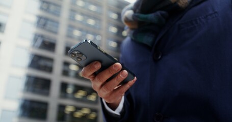 Close-up of male hands typing on a mobile phone, viewed from below. No face, unrecognizable person....