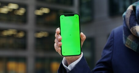 Close-up of a mobile phone with a green screen in the hands of an unknown man. Mockup, copy space, phone screen. Video in 4k, red komodo