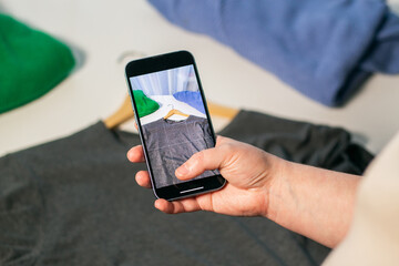 Taking picture of used sweater. Preparing clothes to sell in second hand shop. Second hand and resale concept. Clothes donation.