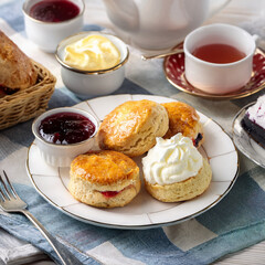 A classic British tea setup with scones, clotted cream, and jam