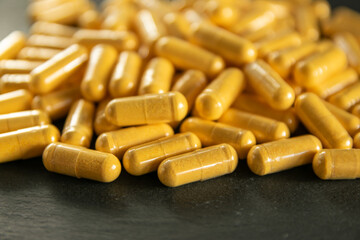 Yellow tabletten or pillen on the black stone background.