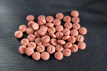 Round tabletten or pillen on the black stone background.