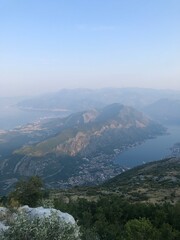 Fototapeta premium The image captures a stunning view of a mountain range, showcasing rugged terrain and highlands. Fog and clouds drift over ridges, while trees dot the valley below, creating a serene outdoor landscape