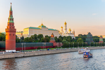 Obraz premium View of Kremlin with Vodovzvodnaya tower, Grand Kremlin Palace from repaired Bolshoy Kamenny Bridge in Moscow city on sunny summer day. Cruise ship sails on the Moscow river