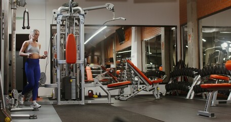 A young woman of European appearance, dressed in a sports uniform, comes to an empty modern gym and starts jumping rope with a focused look
