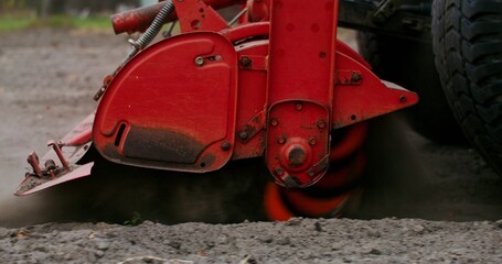 The lowered plow of an agricultural machine is spinning fast, plowing the land, close-up, no people in the video