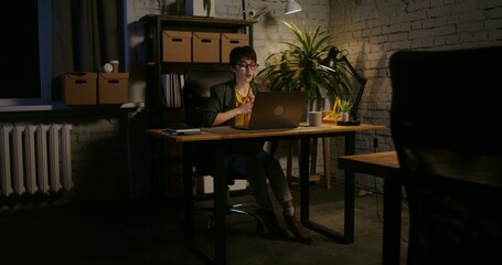 Video conferences on a laptop, online meeting in quarantine. Young beautiful woman of European appearance works at a laptop in the office alone